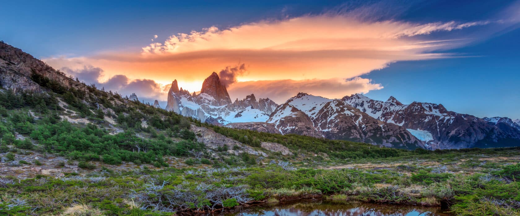 A sunset view of Monte Fitz Roy with a reflection in a pond.