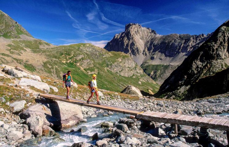 Backpackers crossing a bridge in the French Alps.