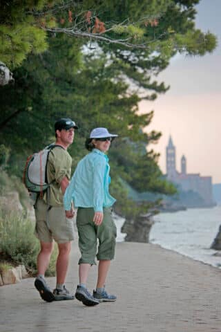 A couple on a walk by a bell tower in Croatia.