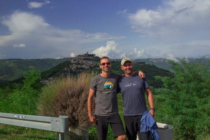 Two men posing in front of a green landscape in Croatia.