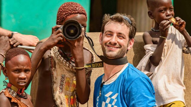 A staff member and kids in Ethiopia learning how to use a camera.