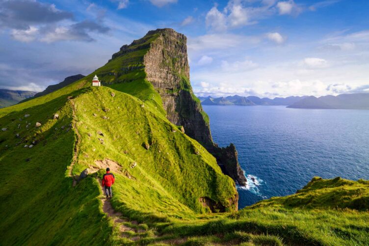 A tourist hiking towards Kallur Lighthouse on Kalsoy island.