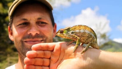 A tourist holding a chameleon.