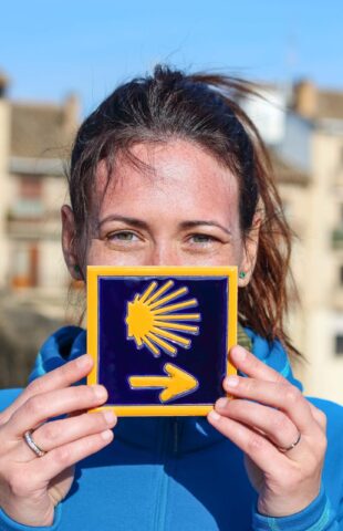 A woman holding a Camino de Santiago tile.